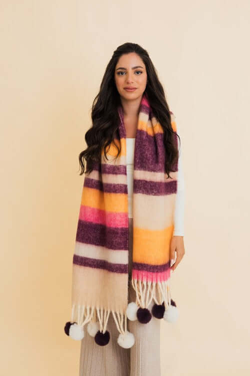 Woman wearing a Contrast Color Stripes Chunky Pom Tassel Scarf in vibrant shades, featuring playful pom tassels and warm design.