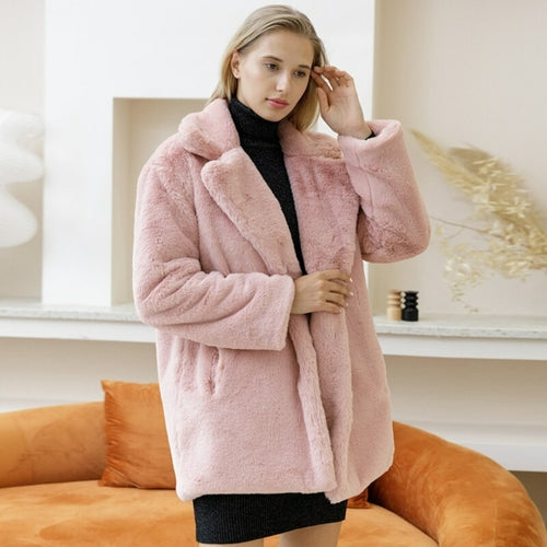 Woman in elegant pink faux fur coat, 2022 Autumn Winter style, with turn-down collar and cozy thick design, standing indoors