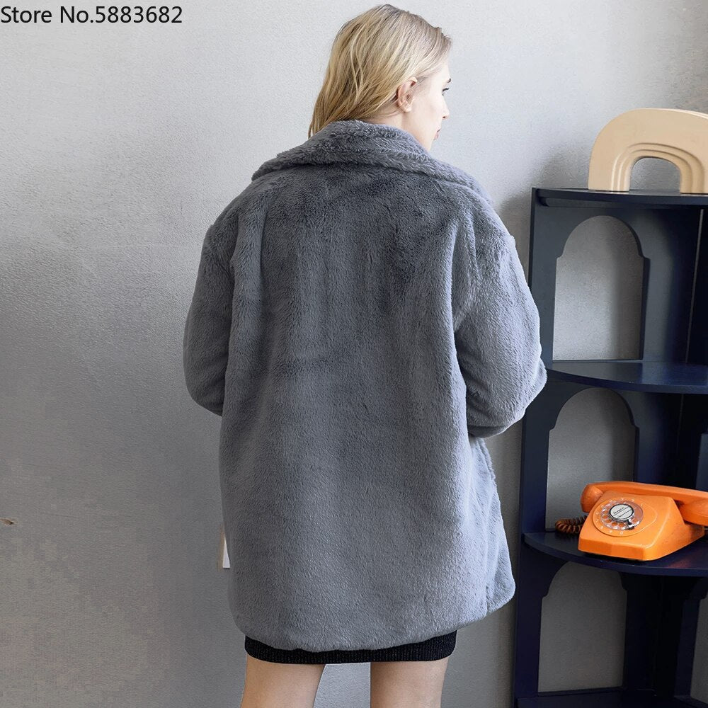 Woman modeling a 2022 Autumn Winter fluffy faux fur coat with turn-down collar, viewed from the back in a minimalist decor setting.