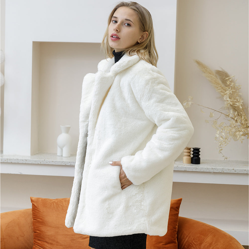 Woman in elegant white faux fur coat posing indoors, showcasing its fluffy texture and sophisticated design for autumn winter 2022.