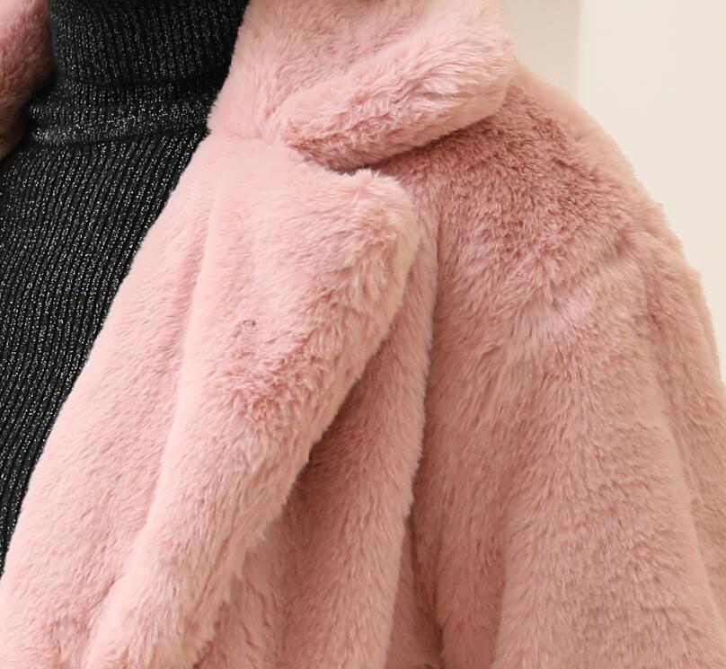 Close-up view of a woman wearing a 2022 Autumn Winter elegant pink faux fur coat with fluffy texture and turn-down collar.