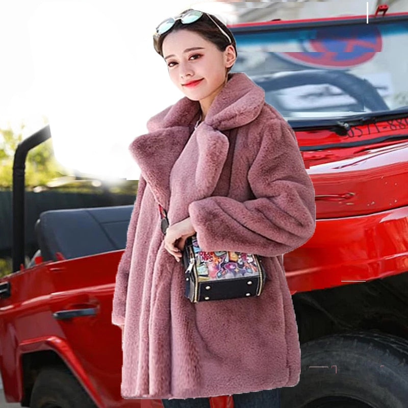 Woman wearing 2022 Autumn Winter faux fur coat, elegant and fluffy, in a stylish mauve color, standing beside a red vehicle.