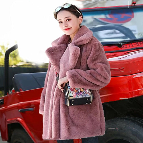 Woman in a stylish 2022 autumn-winter faux fur coat, standing near a red car, enhancing her elegant and warm winter fashion look.