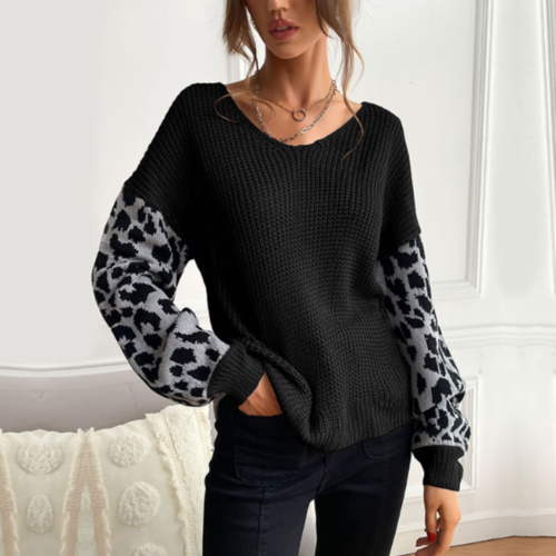 Woman wearing black V-neck sweater with leopard print sleeves in a stylish living room setting