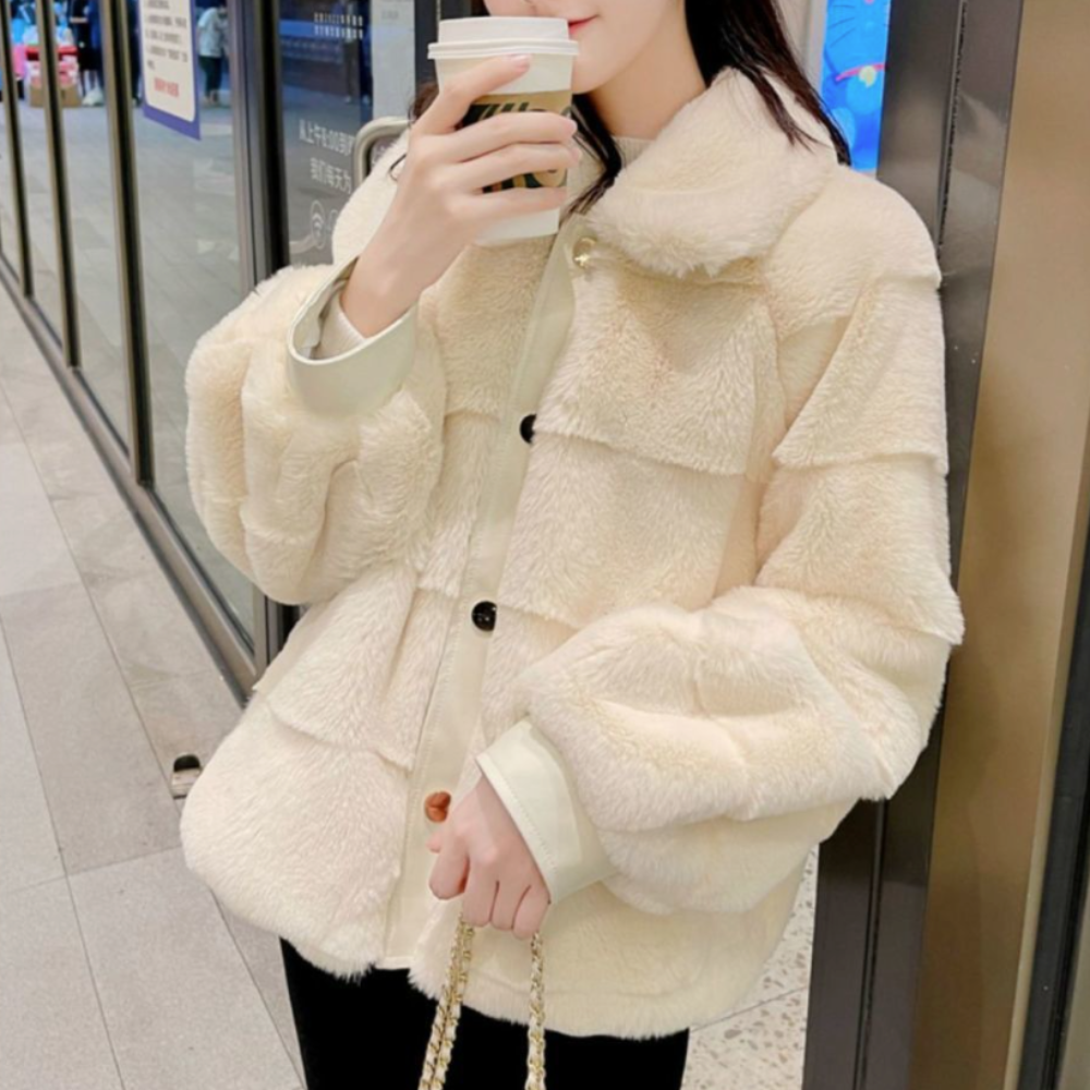 Woman in stylish faux fur jacket with vegan leather trimmed cuffs holding a coffee cup