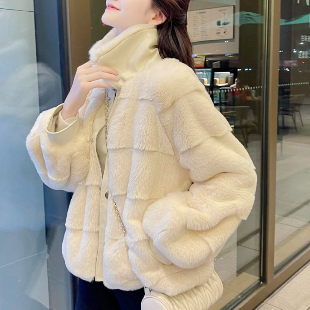 Woman in elegant faux fur jacket with vegan leather cuffs, standing by a cafe window.