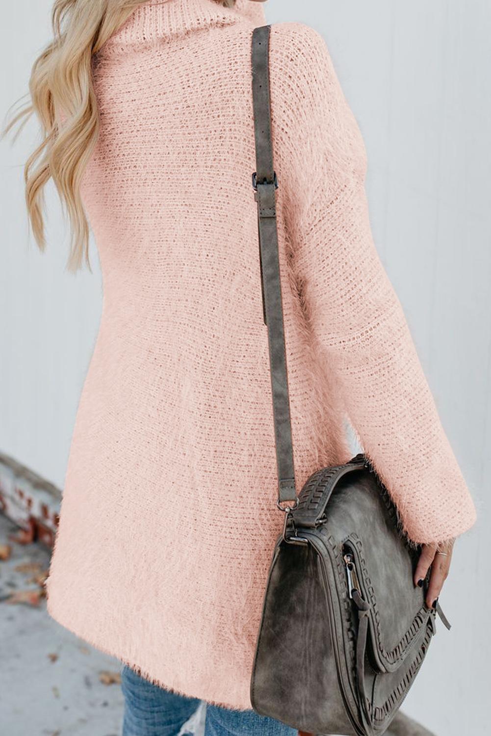 Woman wearing a pink fuzzy double-breasted cardigan with a stylish grey shoulder bag