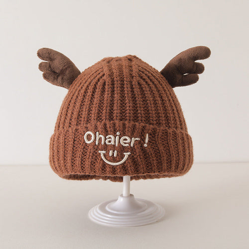 Brown knit baby hat with cute deer antlers and embroidered smiley face on display stand