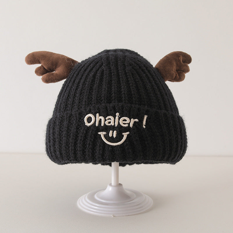 Black knit baby hat with cute deer antlers and "Ohai" face embroidery on display stand