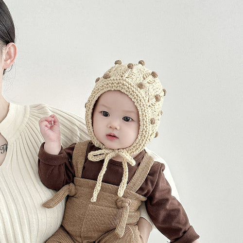 Baby wearing a sweet cute vintage design warm balaclava with dot pattern in beige, held by mother