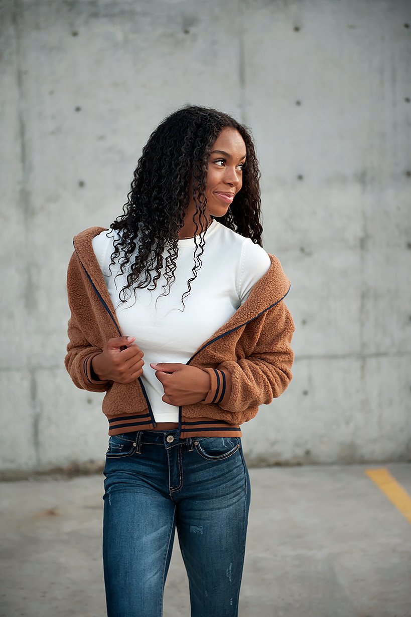 Woman in brown DT Bode Sherpa Winter Jacket smiling in urban setting